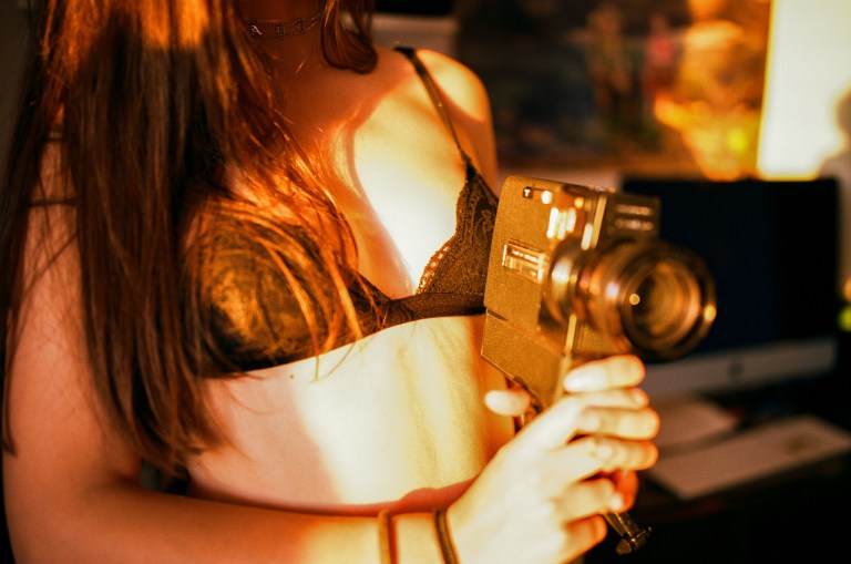 Close up of pretty woman in black bra pointing a camera like a gun