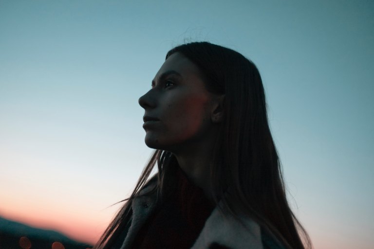 woman standing looking pensive at sunset