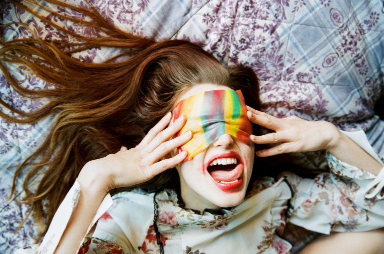 Girl playing with colorful fabric on her face