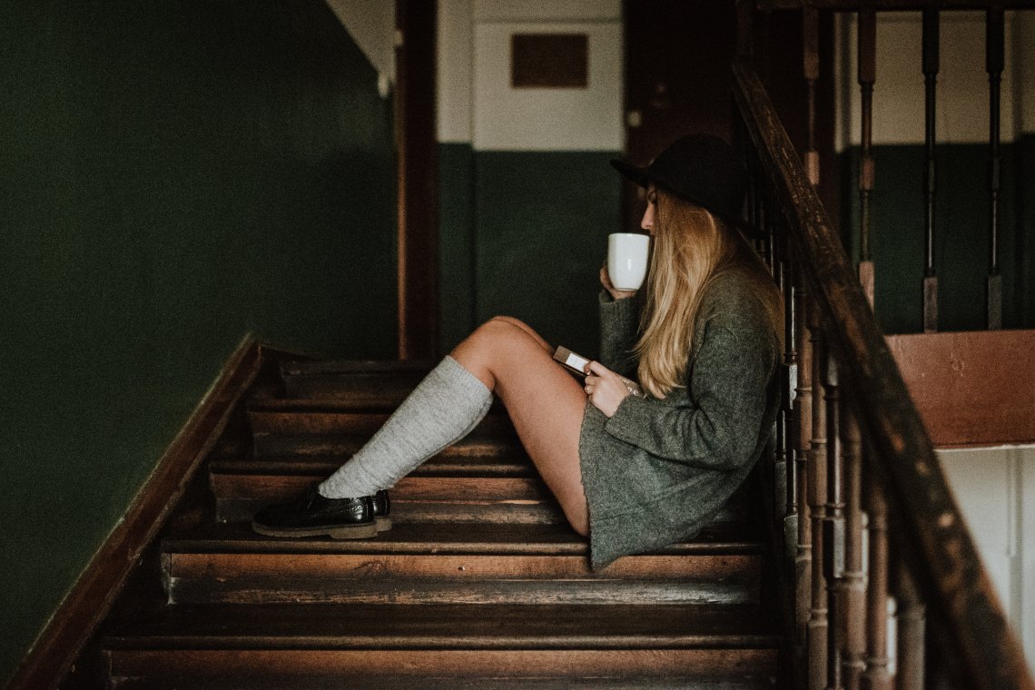 woman sitting on stairs drinking coffee