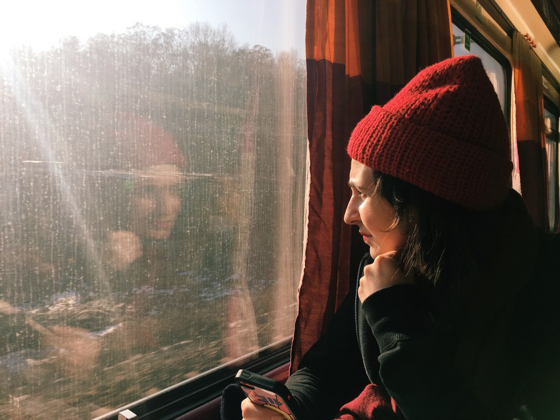 woman staring out window while on phone