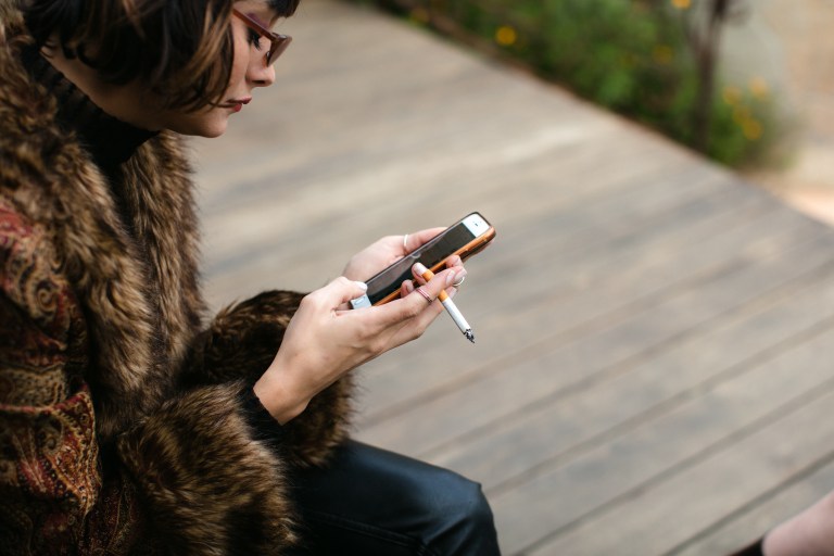 woman smoking cigarette on phone