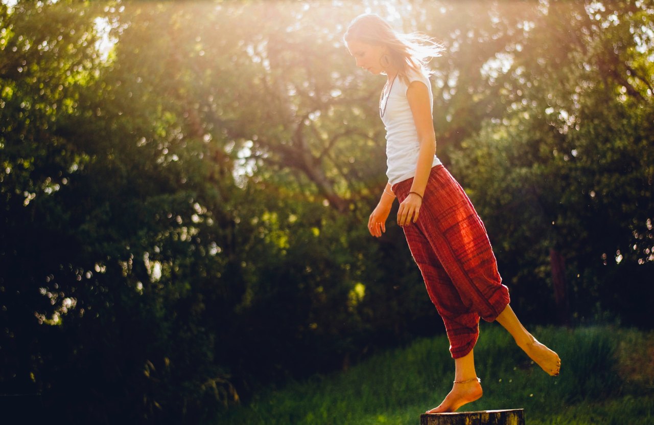 A woman stands on a log in the sunlight