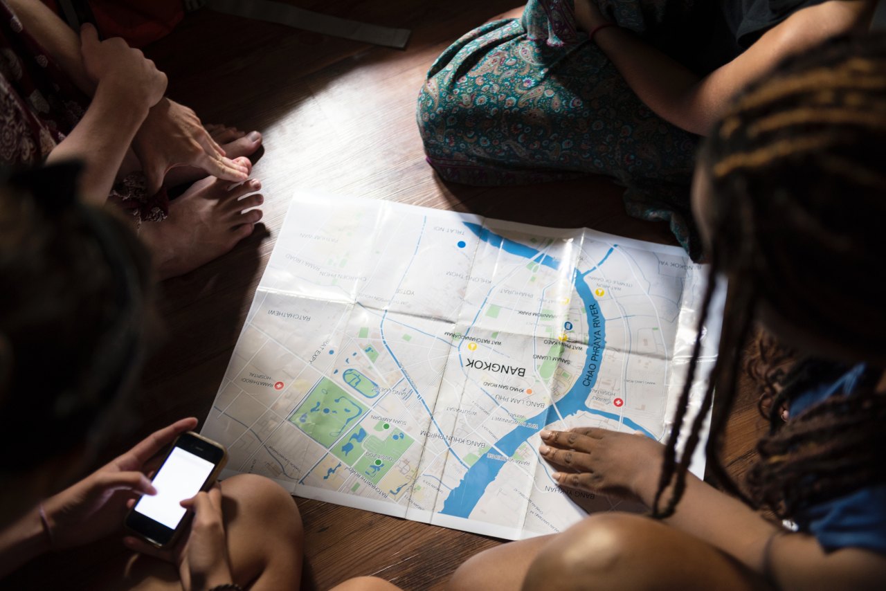 People sitting on a floor looking at a map of Bangkok