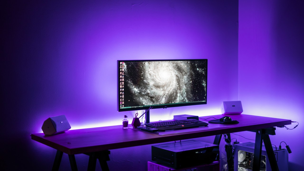 A mac desktop computer surrounded by purple light