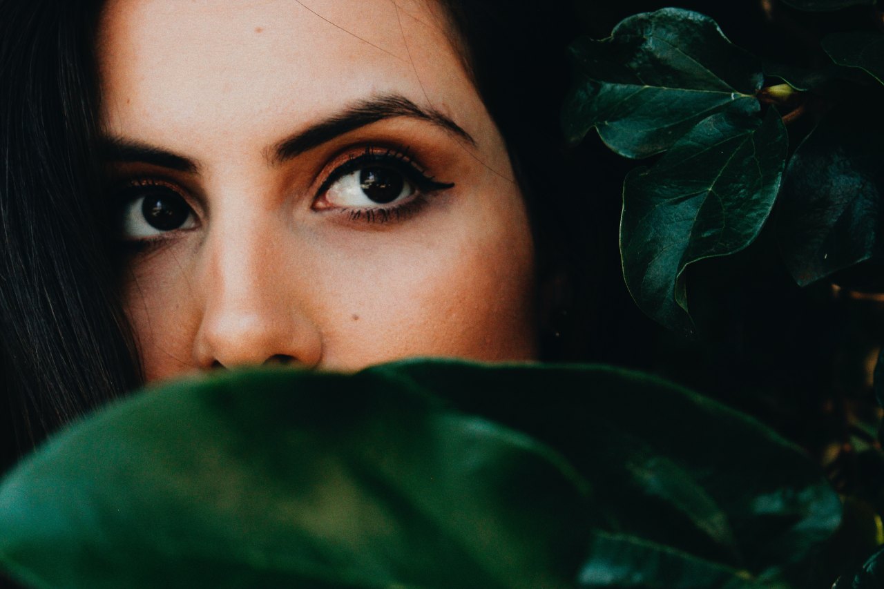 woman looking behind leaves