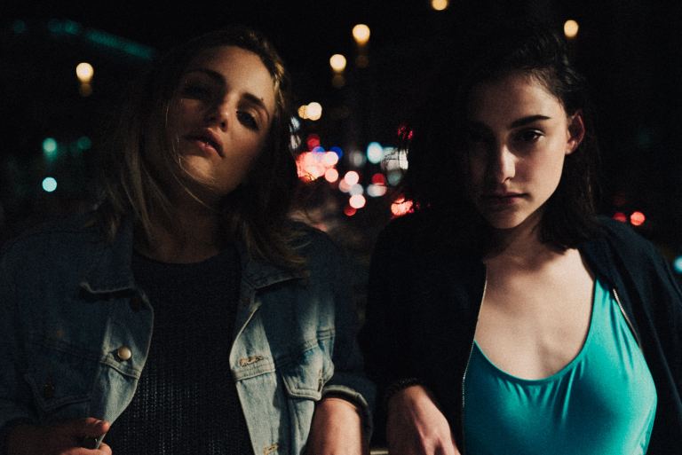 two confident girls standing together at night