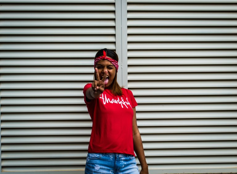 A woman smiles at the camera and holds out the peace sign