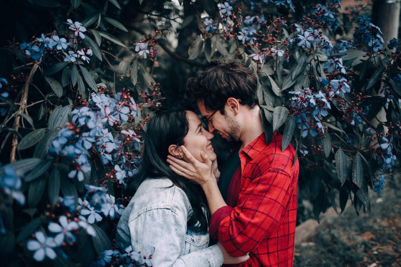 Man Holding Woman's Face Beside Blue Cluster Flowering Plant