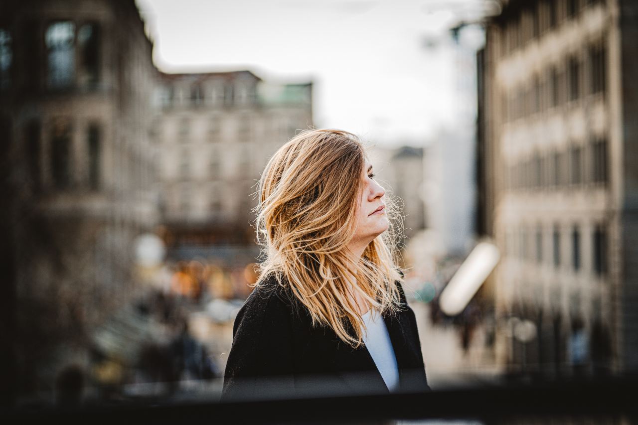 woman in black coat standing near building during daytime