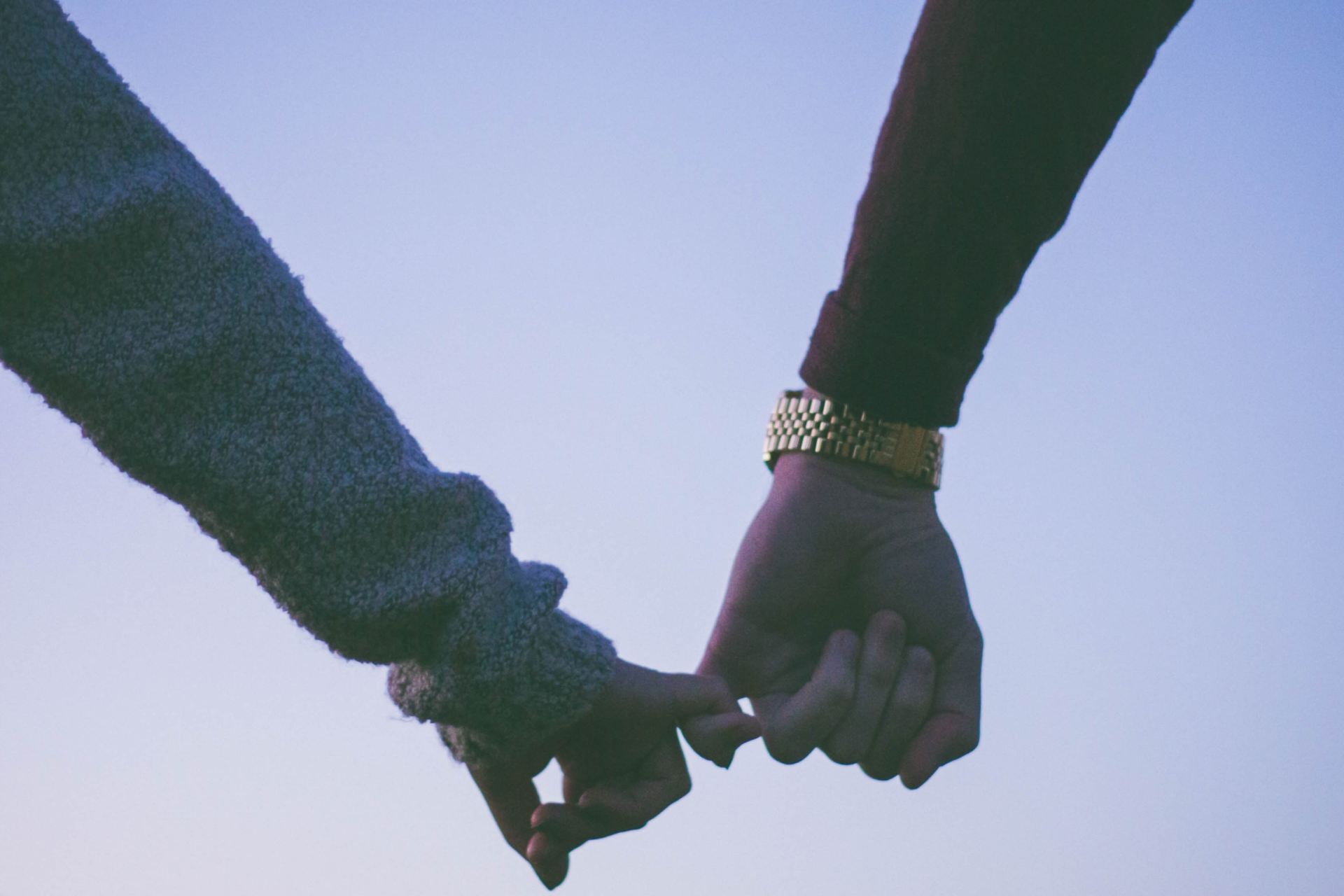 man and woman holding hand using pinky fingers