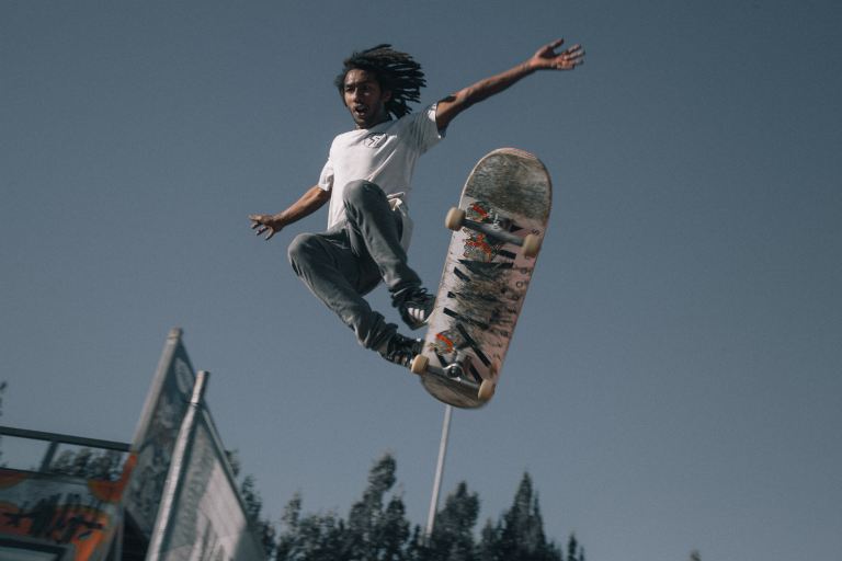 man wearing white T-shirt using skateboard