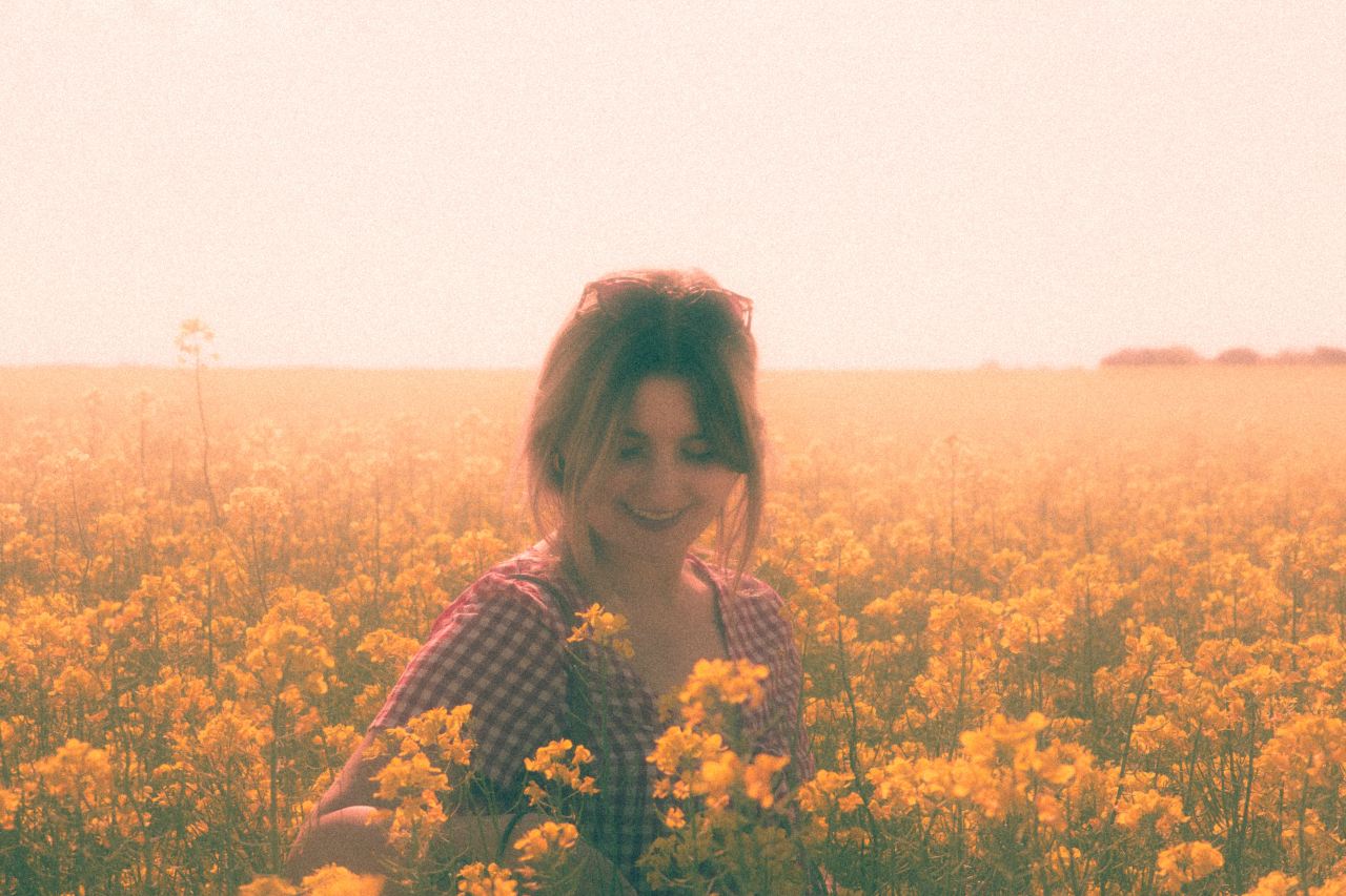 woman in black and white long sleeve shirt standing on yellow flower field during daytime