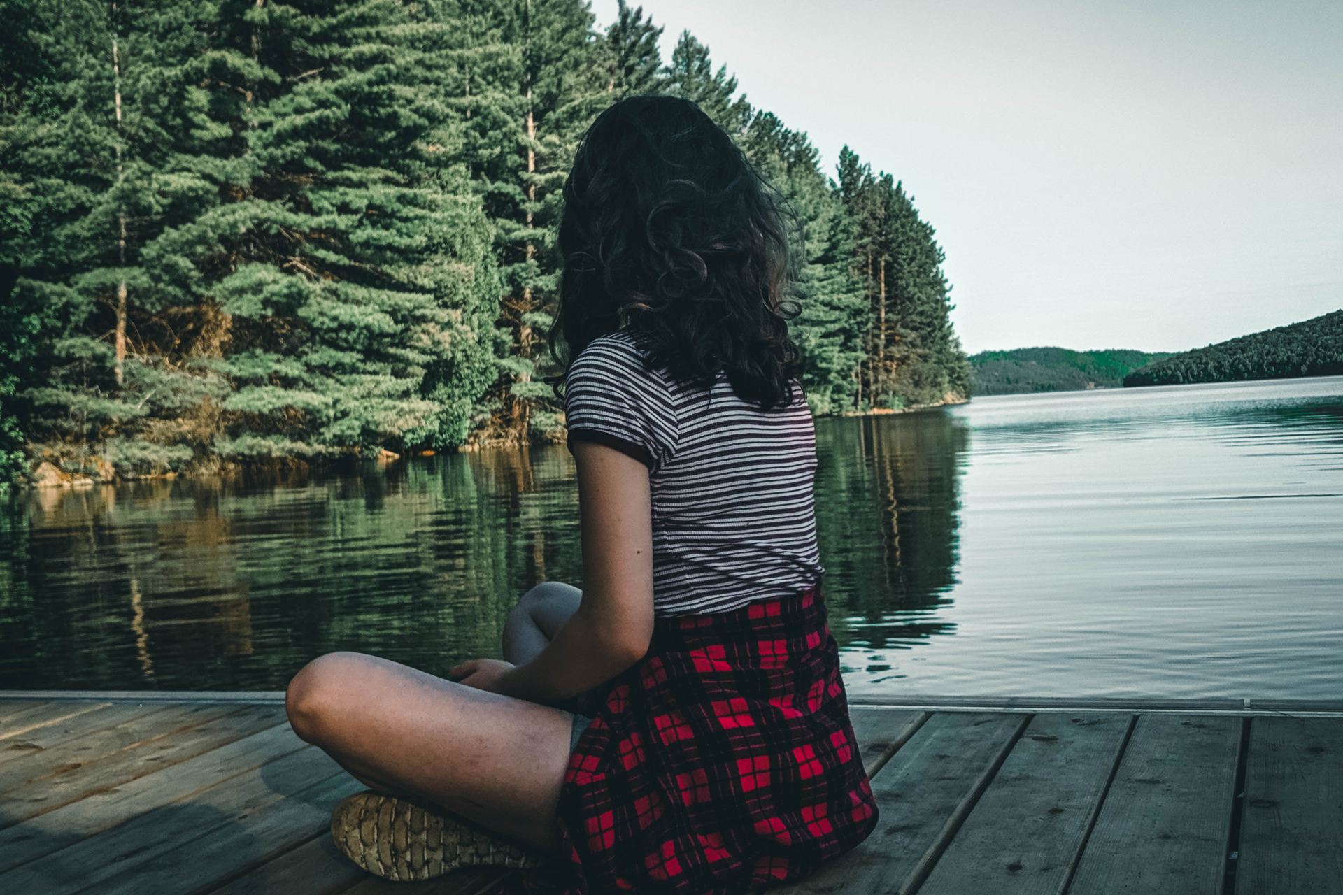 woman in black and white striped shirt sitting on dock during daytime