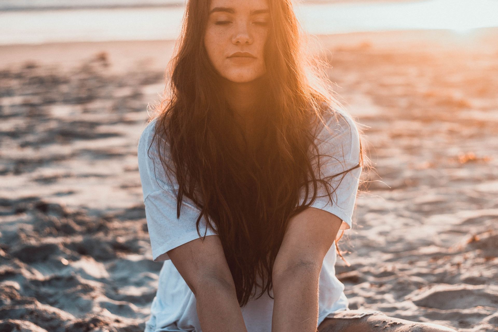 woman sitting on sand holding sands during daytime