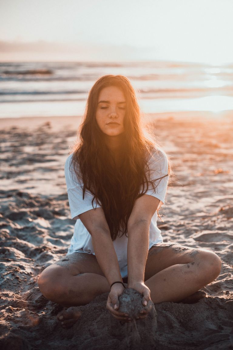 woman sitting on sand holding sands during daytime