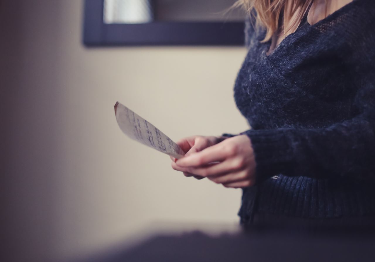 women wearing a black sweater holding a paper close-up photography