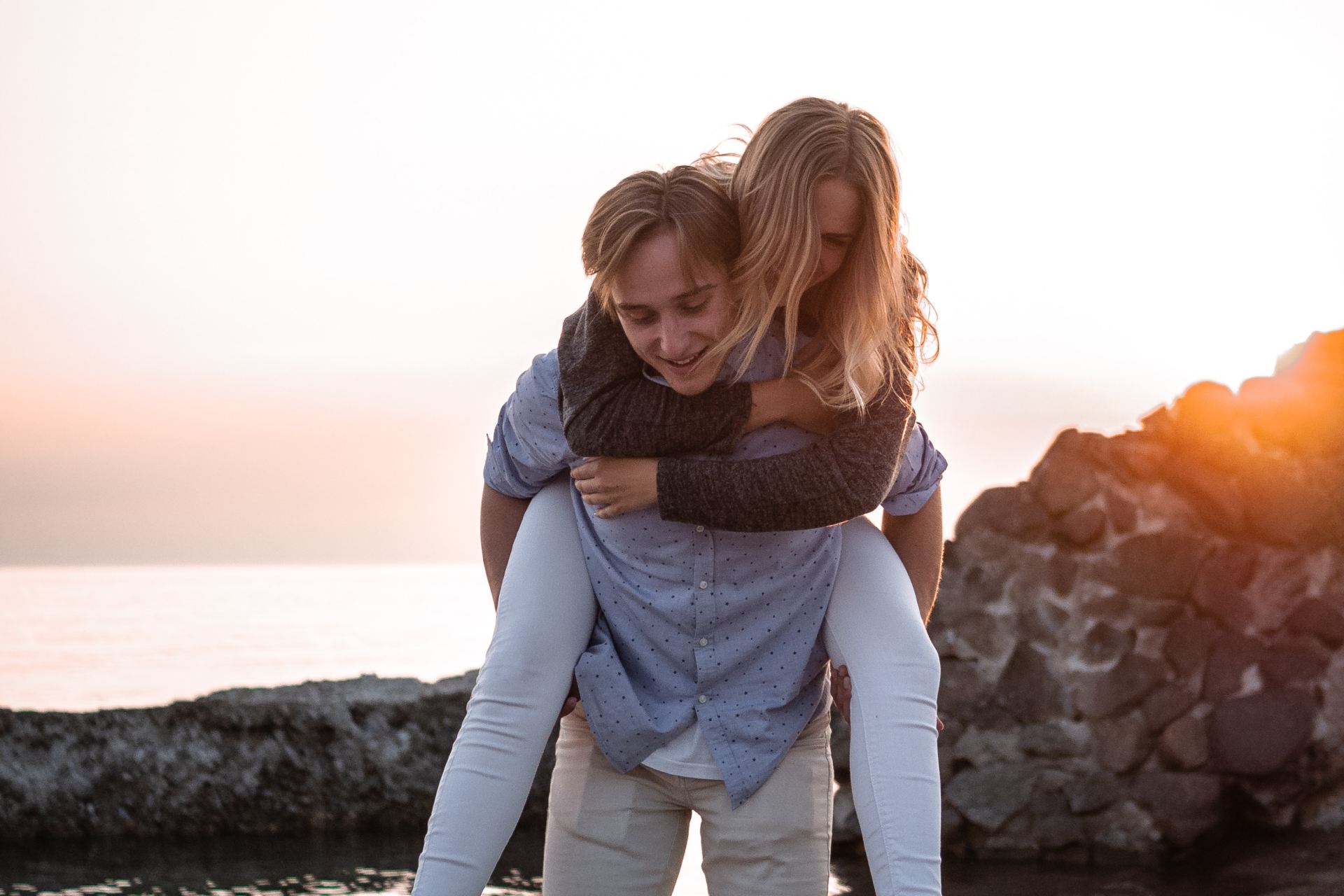 woman hop in on man's back on beach shore