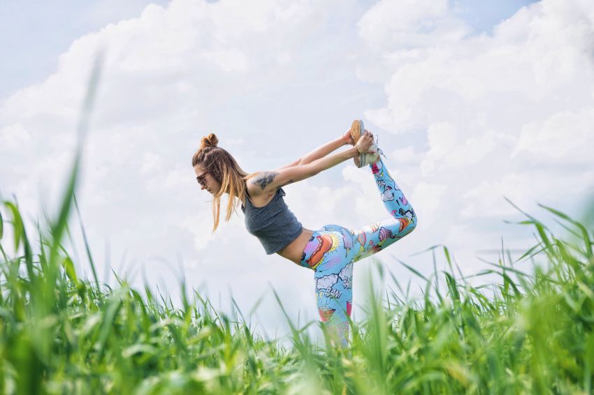 woman standing on left foot while lifting right foot upwards during daytime