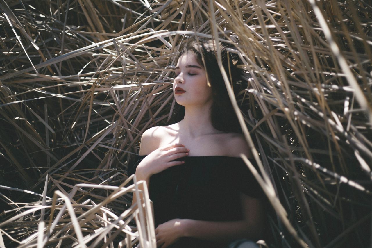 woman in black off-shoulder top laying in haystack