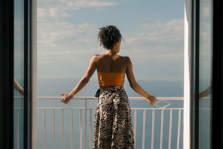 woman wearing orange tube and black skirt facing terrace