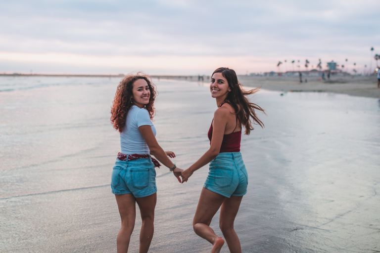 2 women in blue and white tank top standing on beach during daytime