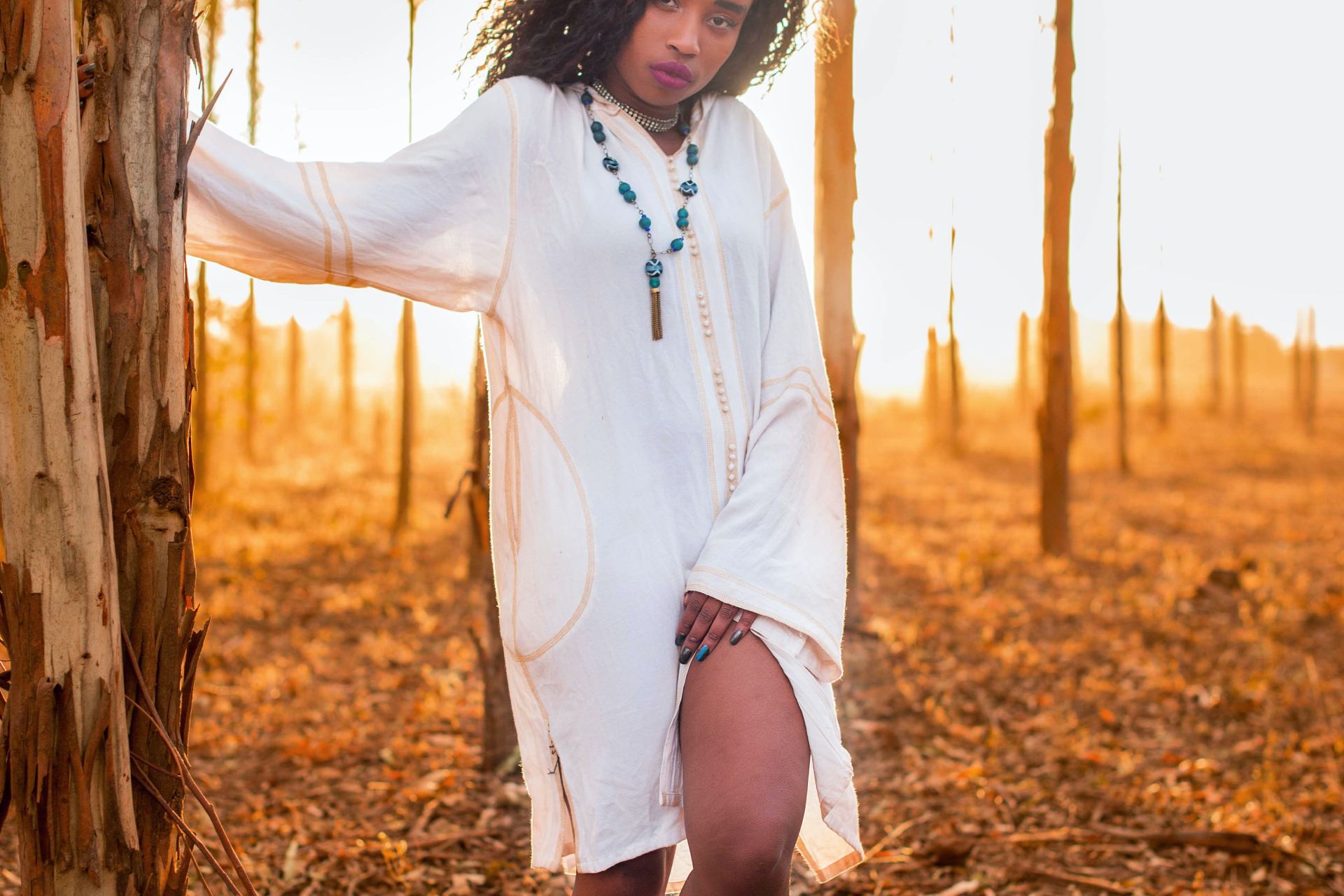 woman in white long-sleeved dress near tree during daytime