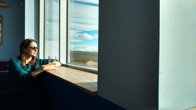 woman sitting beside window while looking outside