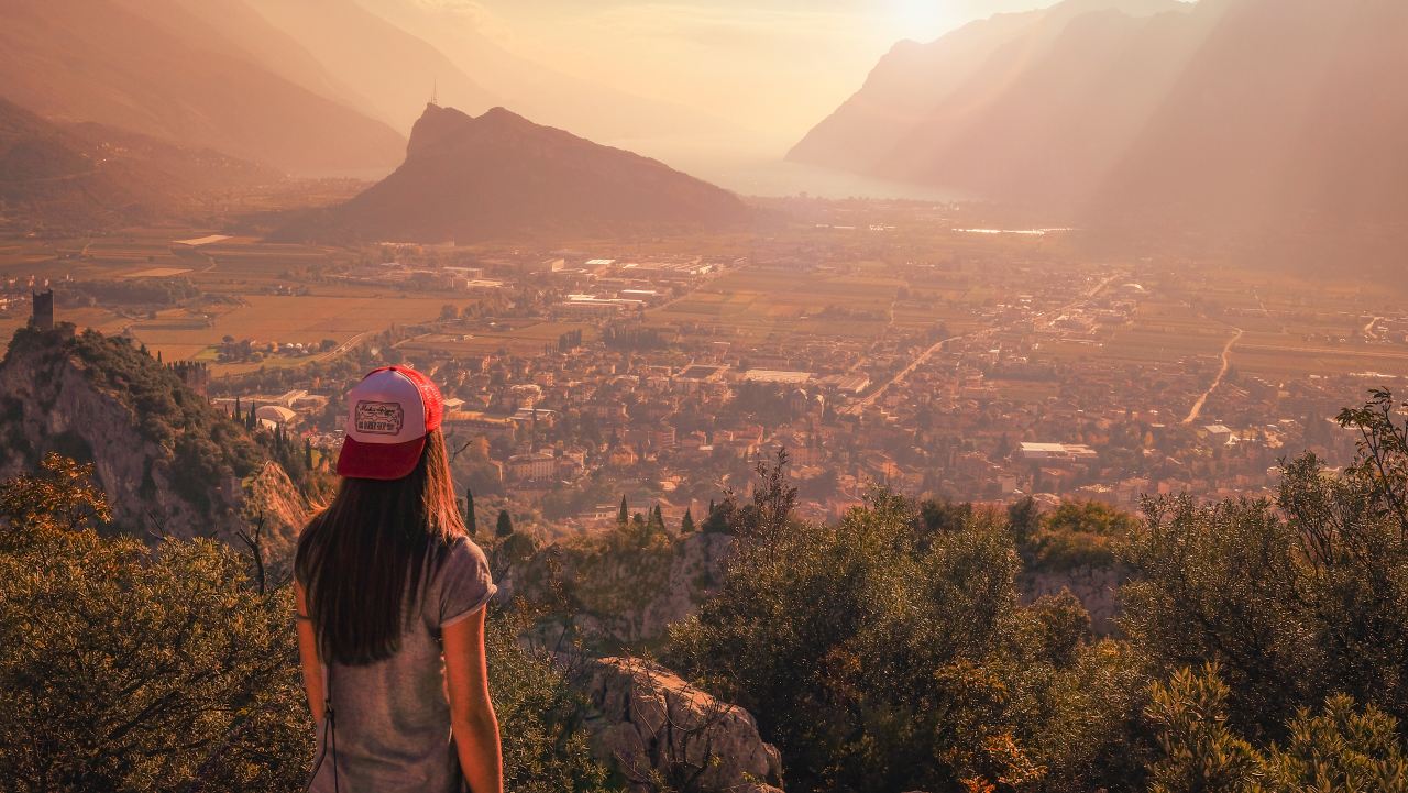 woman wearing gray shirt facing town near mountain during daytime