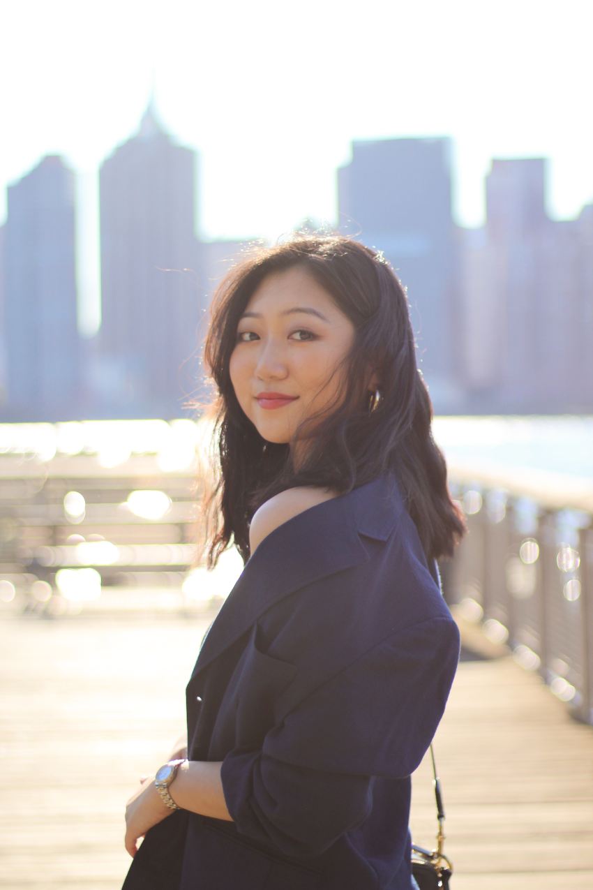 woman in black blazer standing on sidewalk during daytime