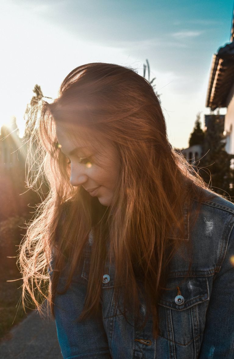 woman wearing blue denim jacket looking on her right side in shallow focus photography