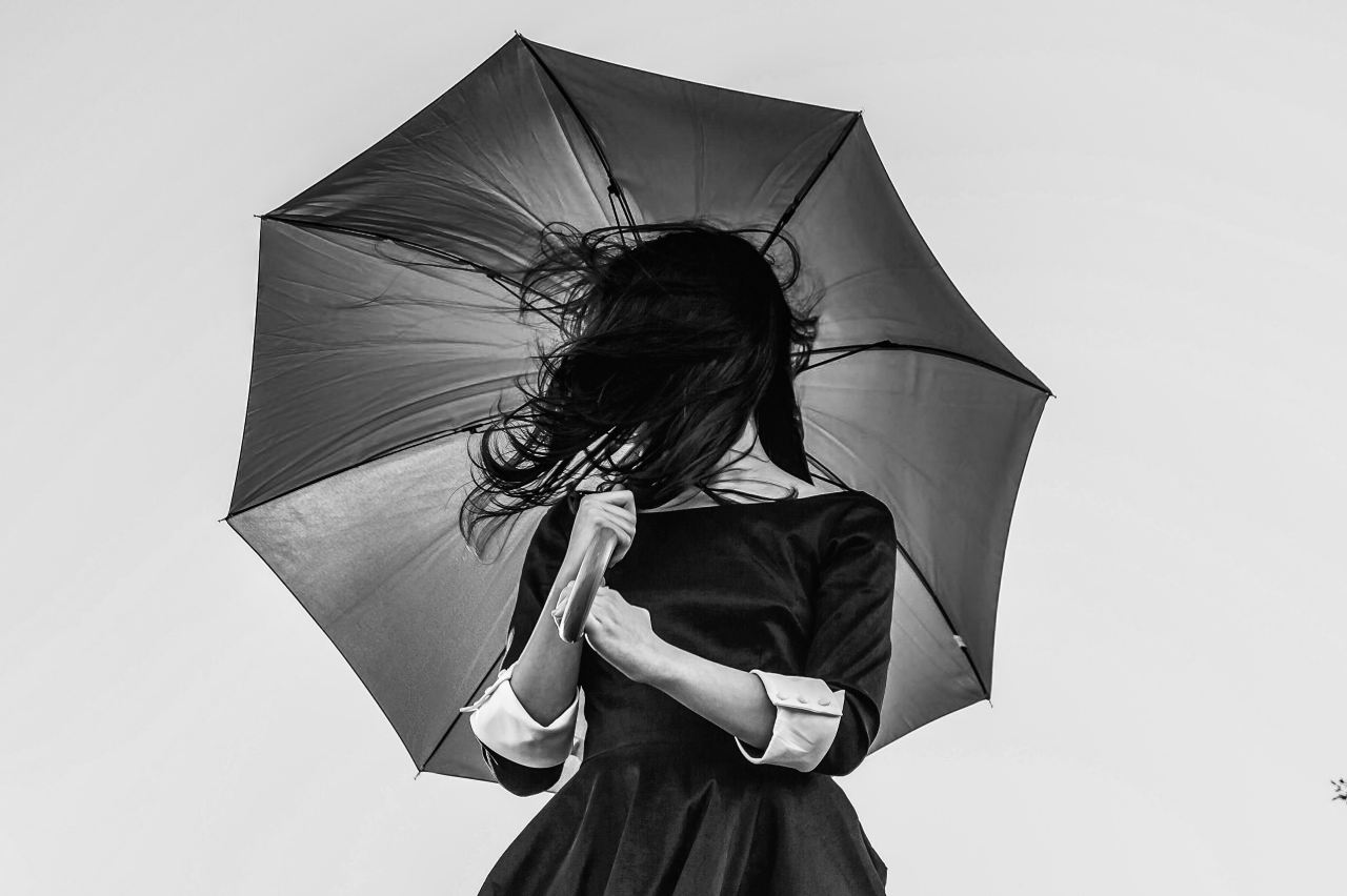 grayscale photo of woman holding umbrella