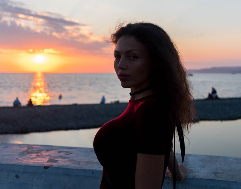 woman in red long sleeve shirt standing on beach during sunset