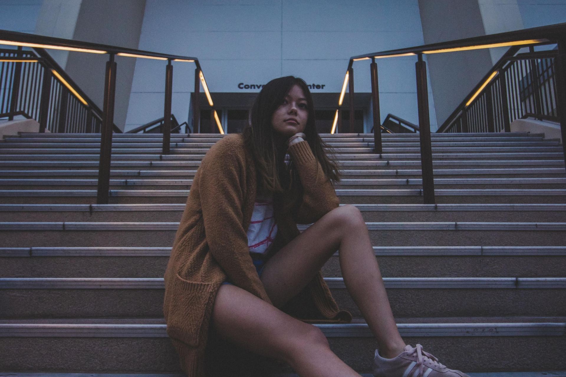 woman in brown coat sitting on stairs