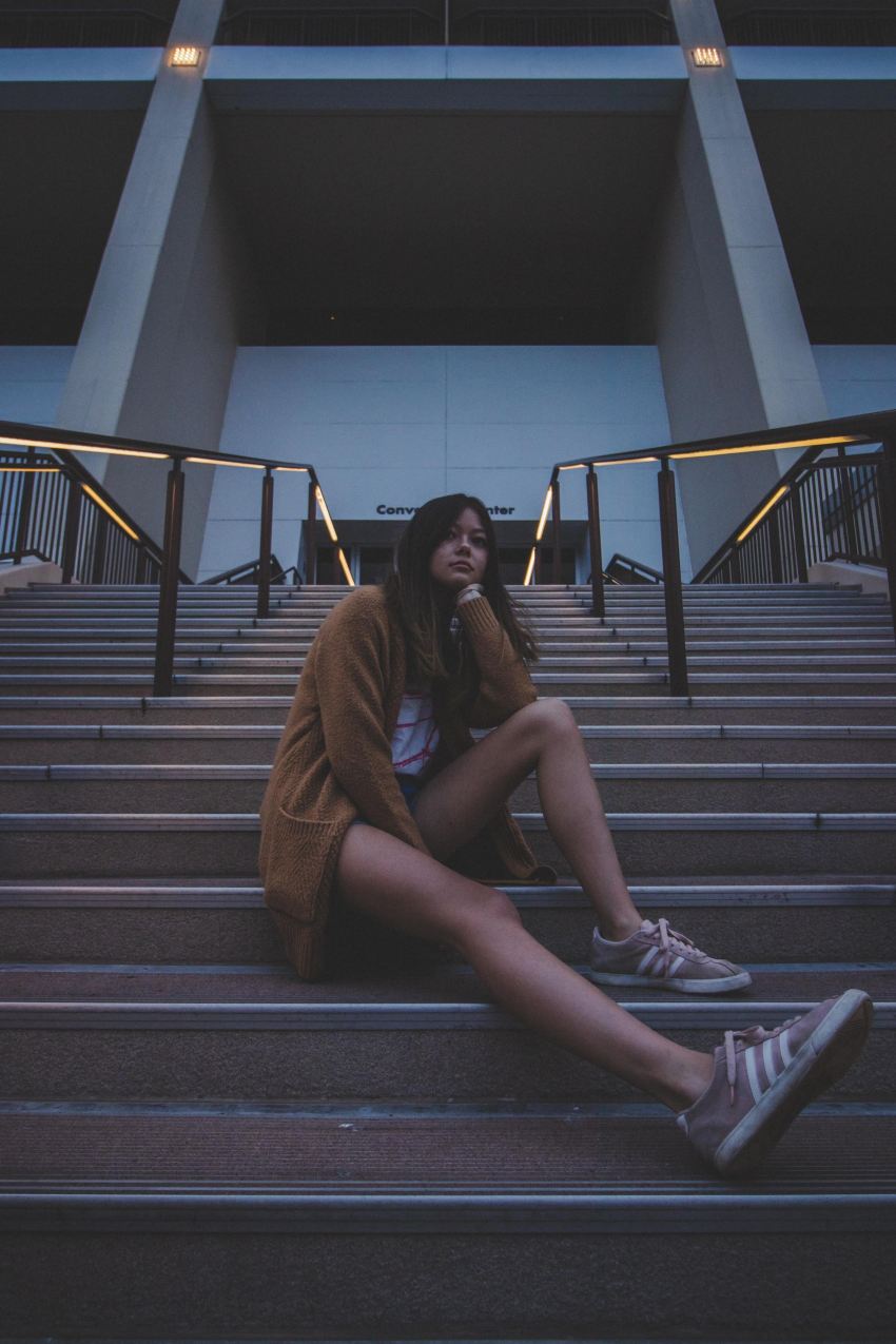 woman in brown coat sitting on stairs