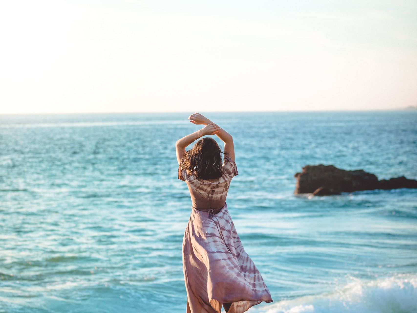 woman standing on cliff raiser her hands