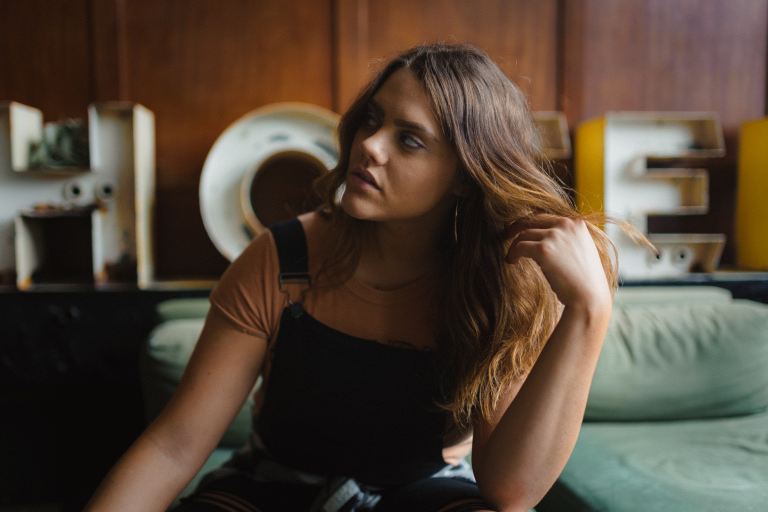 woman in black tank top and black pants sitting on green bed