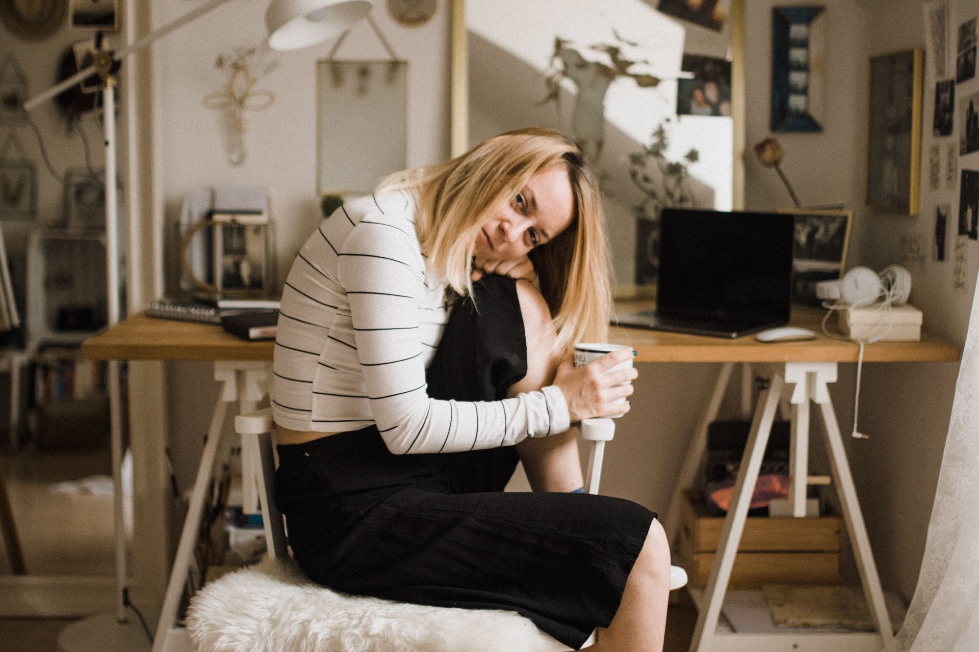 woman sitting on stool resting her head on her knee inside room