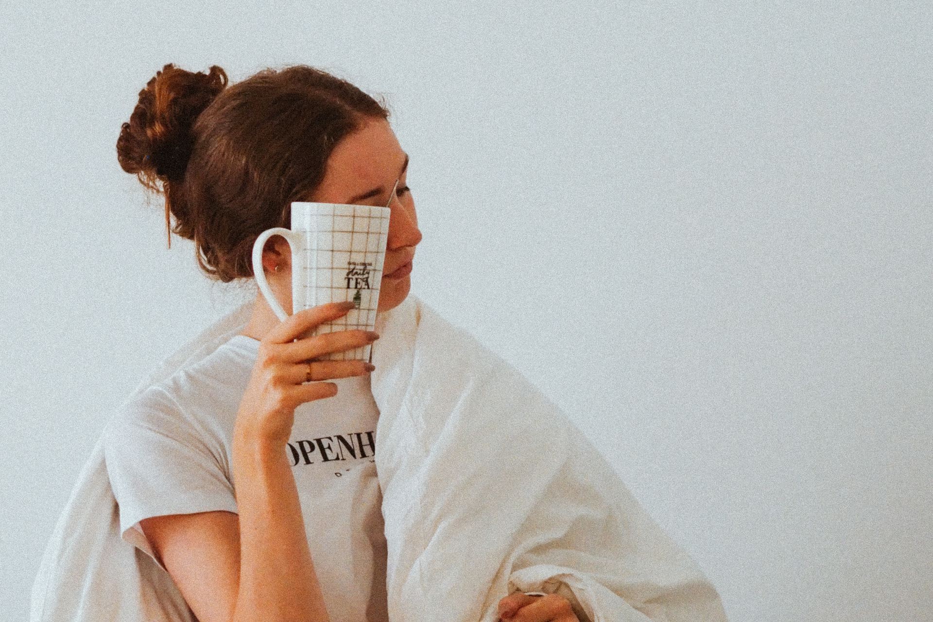 woman in white robe holding white ceramic mug