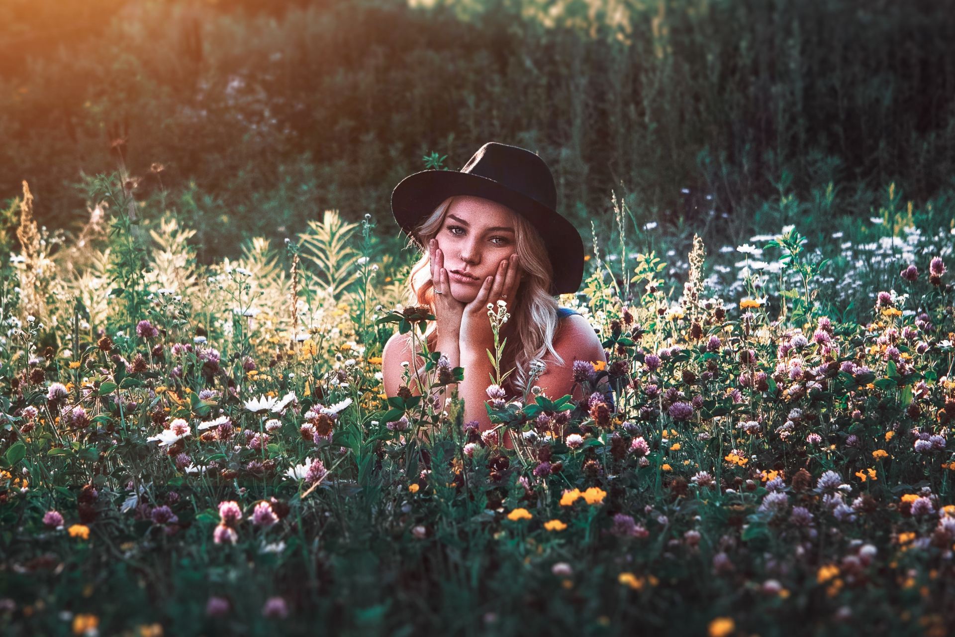 woman in black hat on flower field during daytime