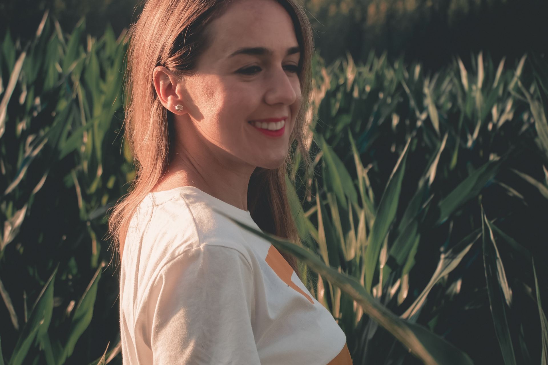 woman smiling beside green leaves during golden hour