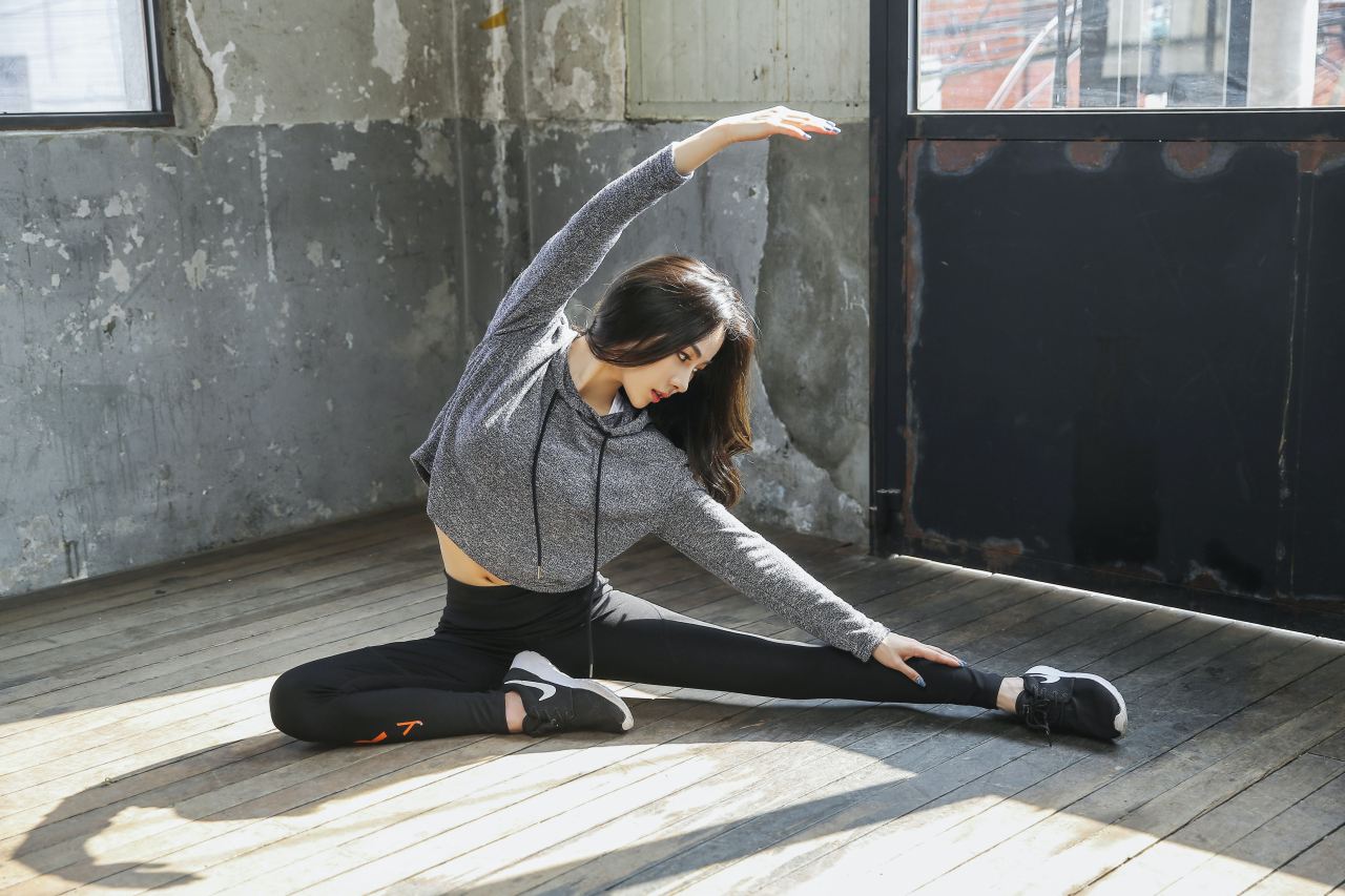 woman in gray long sleeve shirt and black pants sitting on wooden floor