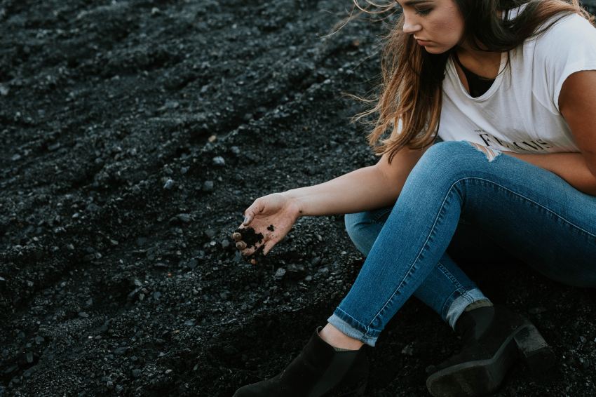 woman sitting on soil with denim jeans and white shirt