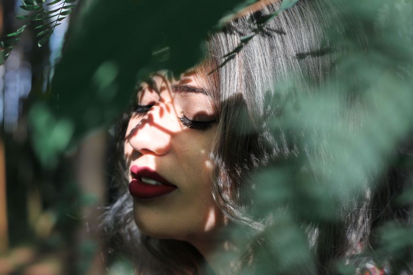 woman closing eye near leaf