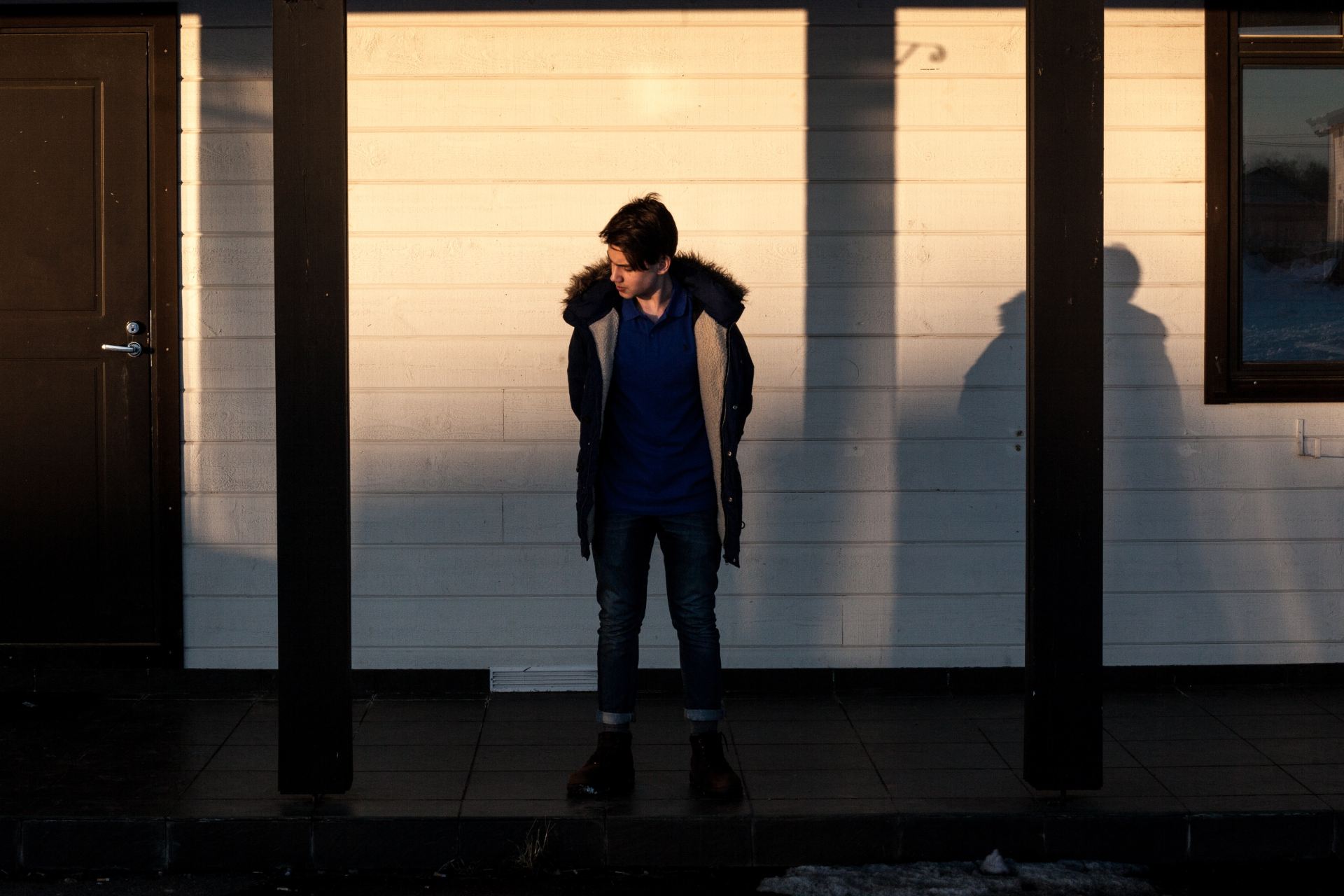 man in black fur jacket standing in the middle of wooden posts