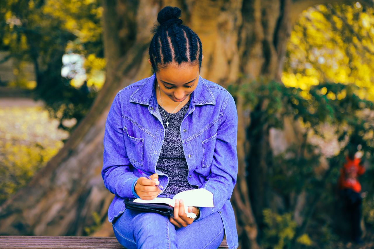 selective focus photography of woman reading book while sitting at bench