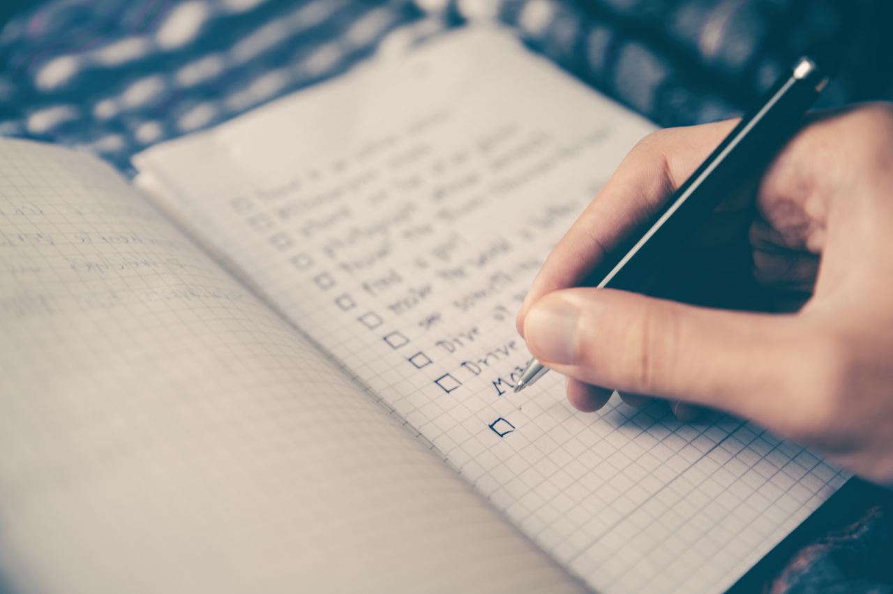 person writing bucket list on book