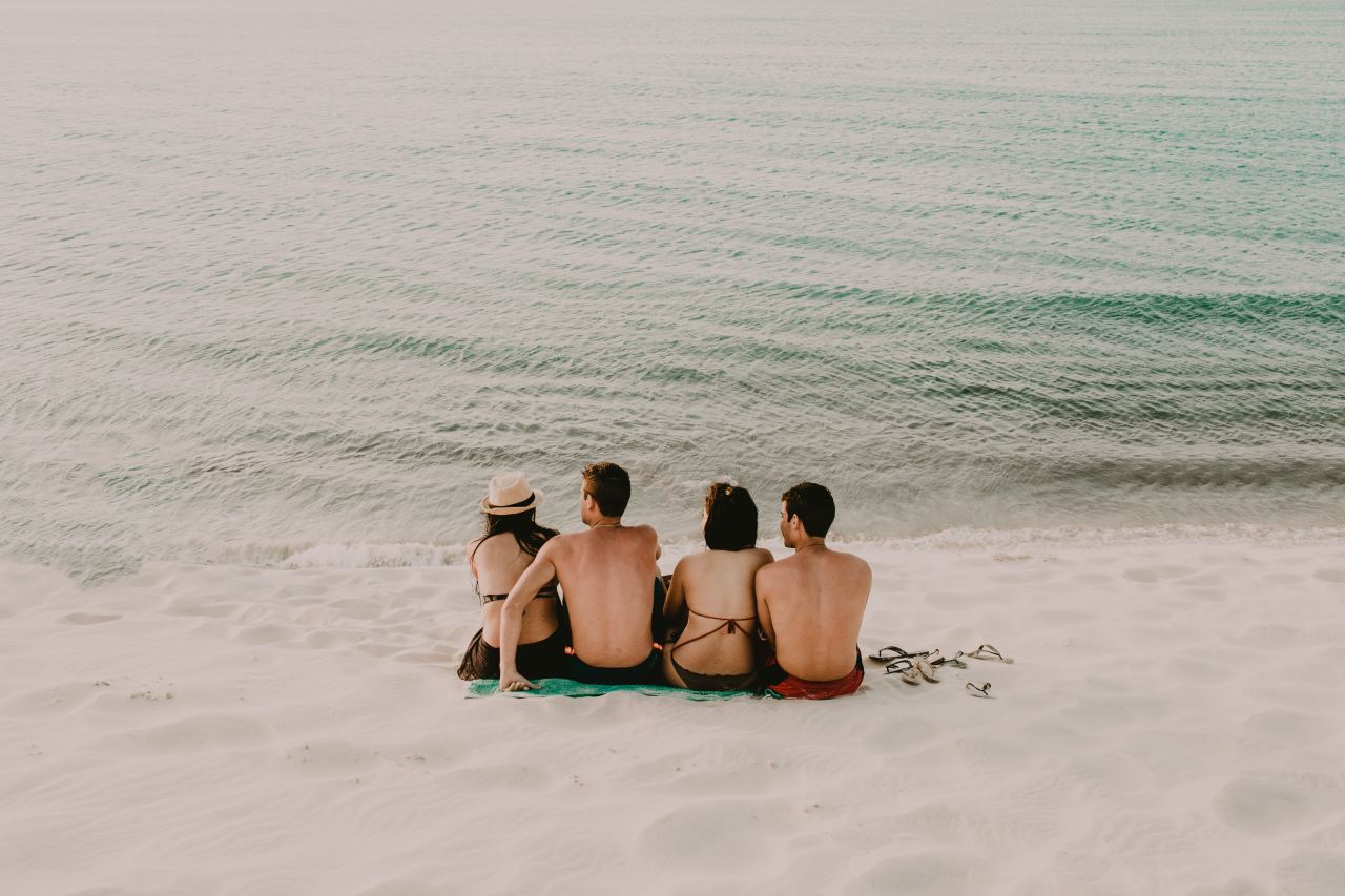 two men and women sitting on shore