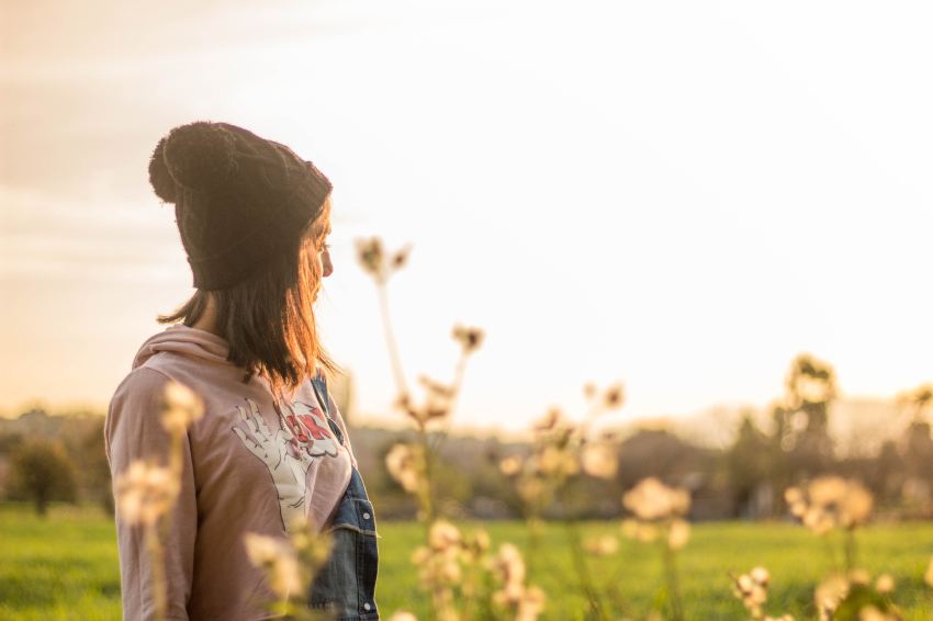 woman standing on grass field looking at trees