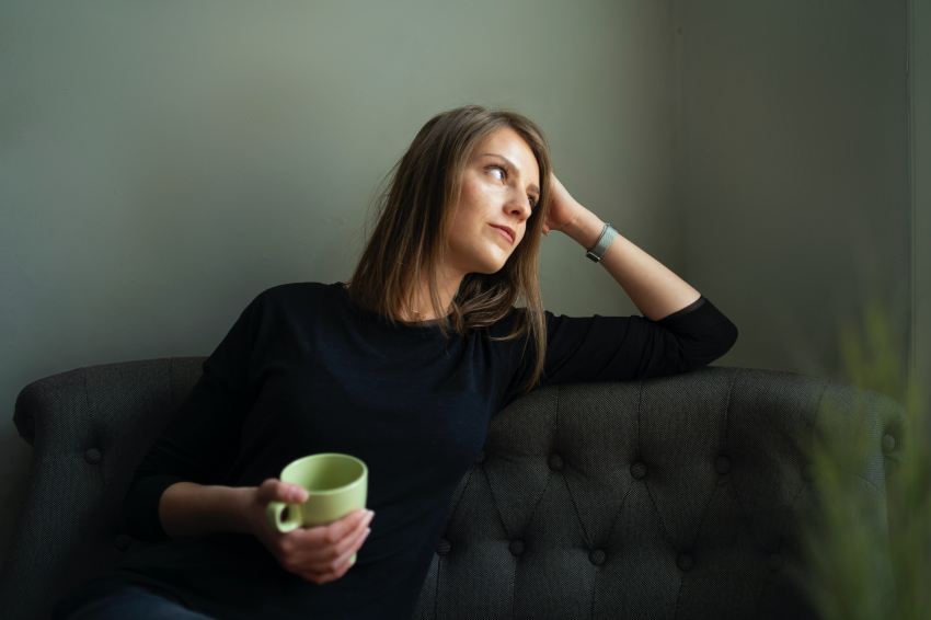 woman in black crew neck t-shirt holding green ceramic mug sitting on black sofa